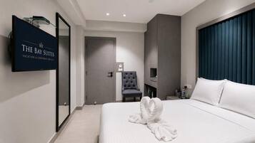Una habitación de hotel con una cama, un televisor de pantalla plana, una silla y un escritorio.