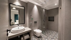 A modern bathroom with a large mirror, a sink, a toilet, and a shower. - The Bay Suites - Residency (New Town)