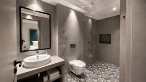 Een moderne badkamer met een grote spiegel, een wastafel, toilet en douche.
