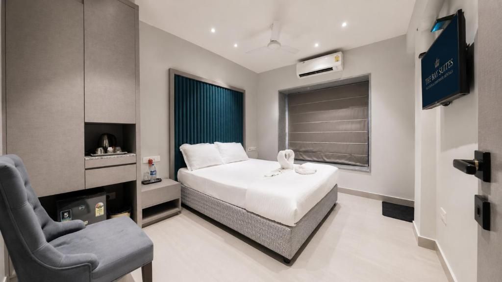 Una habitación de hotel moderna con una cama, una silla, un televisor y un equipo de aire acondicionado de pared.
