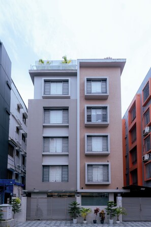 A multi-story building with a flat facade, multiple windows with shutters, and a gated entrance.