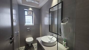 A bathroom with a toilet, sink, and a mirror.