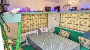 Une chambre avec des lits superposés, une couvre-lit à pois et une étagère remplie de divers objets.