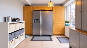 A modern kitchen with a stainless steel refrigerator, wooden cabinets, and a pet feeding station. - Hideaway House, Sleeps 6 with Hot Tub & Balcony (Chester Le Street)