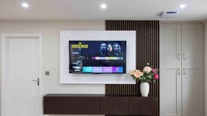 A flat-screen TV mounted on a wall with a selection of streaming services displayed. - Meigh Village Apartment (Newry)