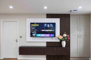 A flat-screen TV mounted on a wall with a selection of streaming services displayed. - Meigh Village Apartment (Newry)