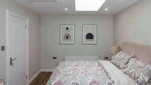 A bedroom with a bed, a door, a radiator, and two wall-mounted pictures. - Meigh Village Apartment (Newry)