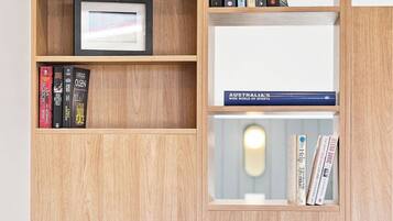 A wooden bookshelf with books, a framed picture, and a table with two chairs.