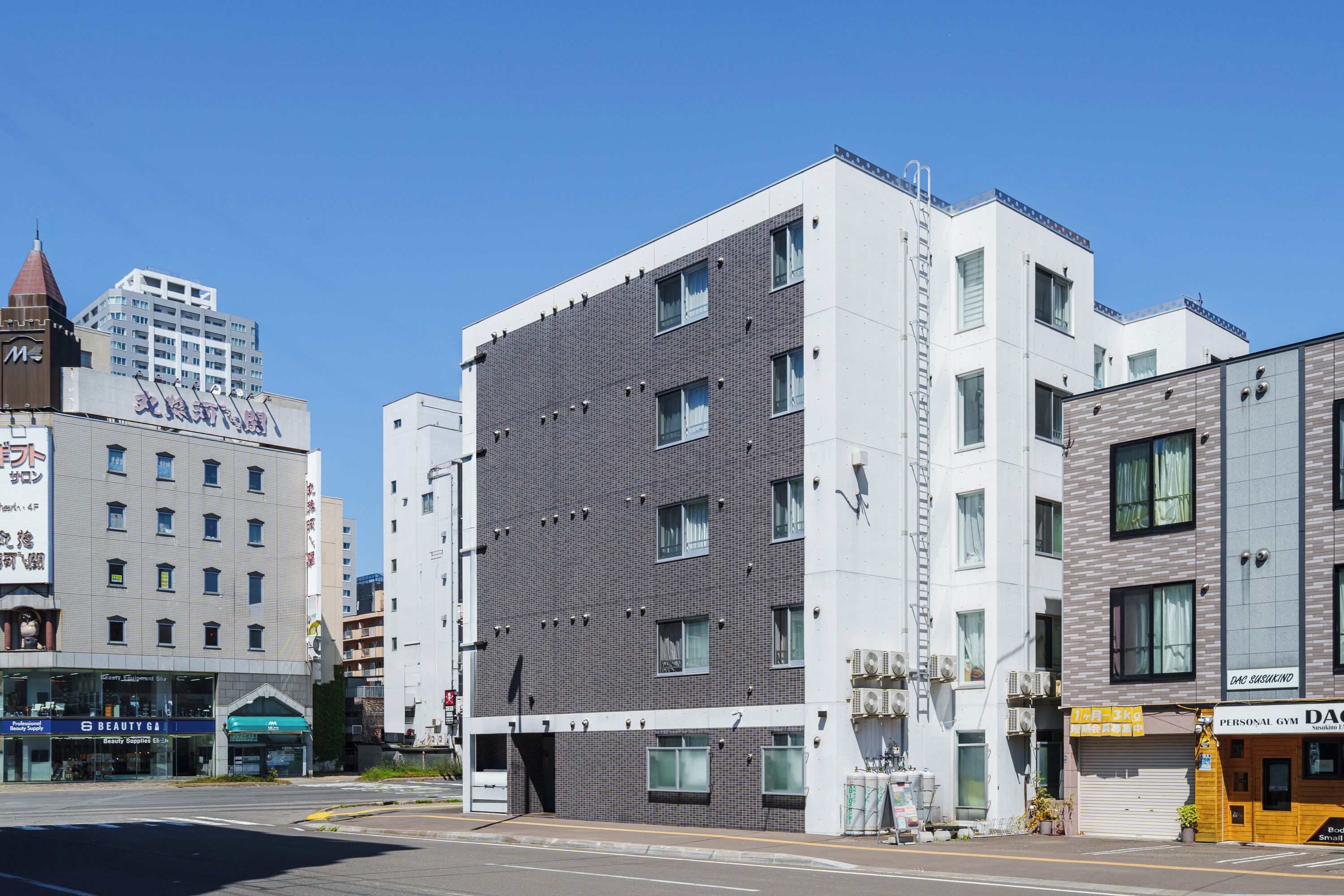 A multi-story building with a modern architectural design, featuring a mix of brick and white facades, and several windows.