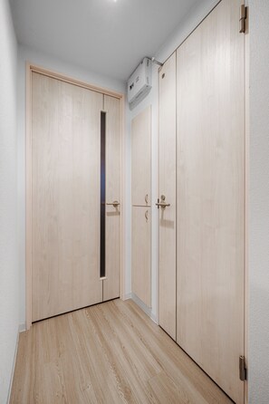 A room with a wooden wardrobe, a door with a vertical handle, and a light-colored floor. - SONIA 103 (Sapporo)