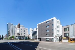 Eine moderne Stadtstraße mit mehrstöckigen Gebäuden, blauem Himmel und einer Fußgängerampel.