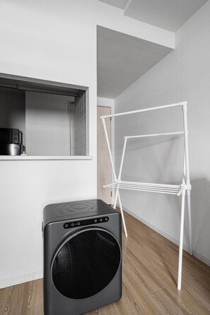 A laundry area with a washing machine and a drying rack. - SONIA 103 (Sapporo)