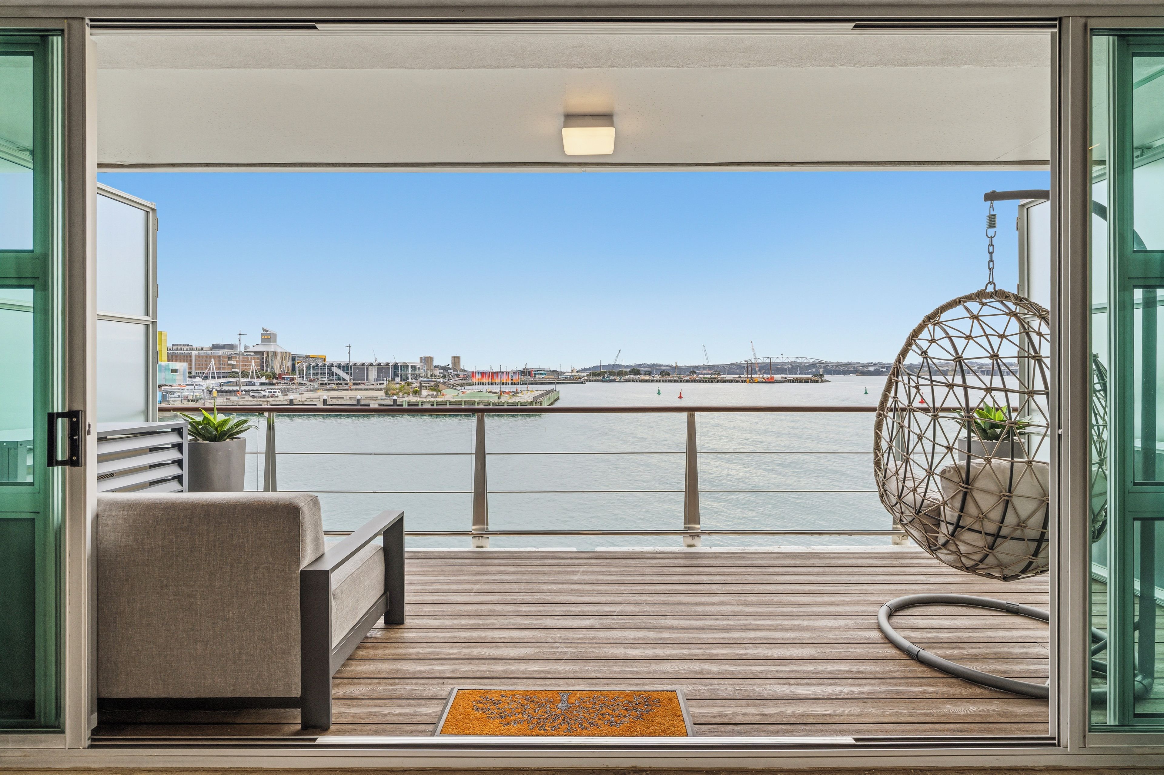 Un balcon donnant sur le bord de l’eau, une chaise suspendue et un banc.