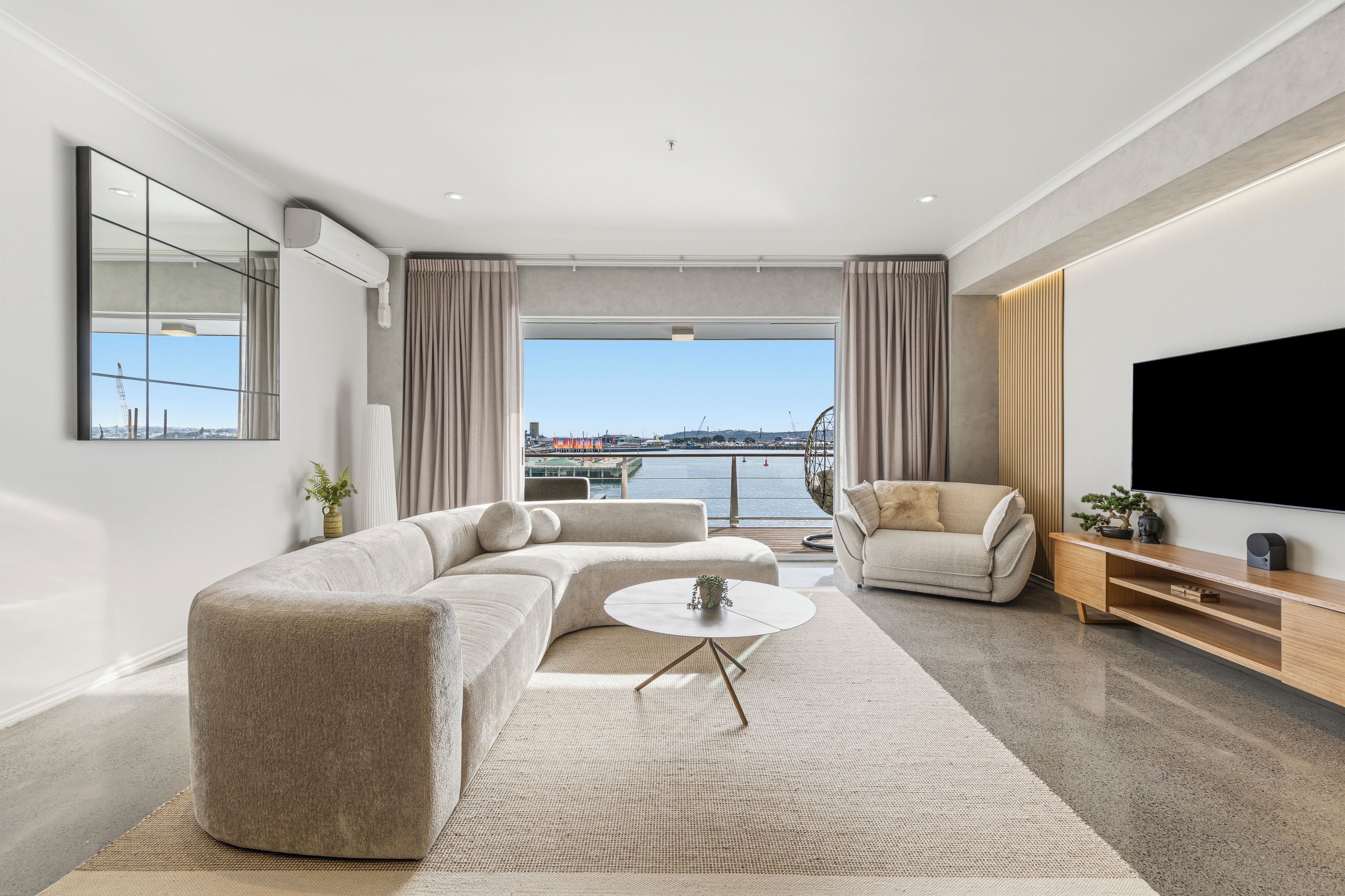 Een moderne woonkamer met een modulaire bank, een ronde salontafel en een flatscreen televisie.