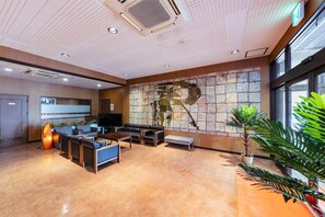 A spacious lobby with a seating area, a large wall art piece, and a potted plant. - Mango Hotel Nichinan (Nichinan City Iwasaki)