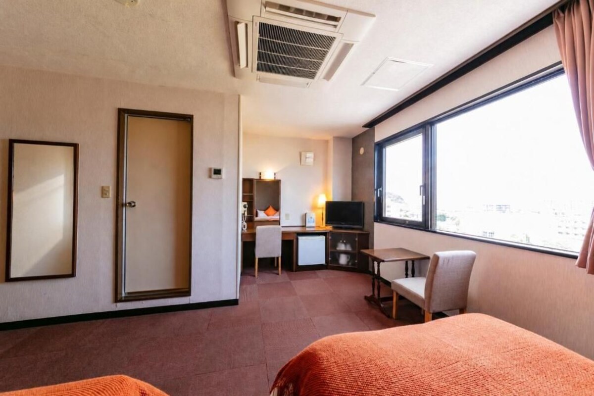 A hotel room with a bed, a desk, a television, and a window with curtains.