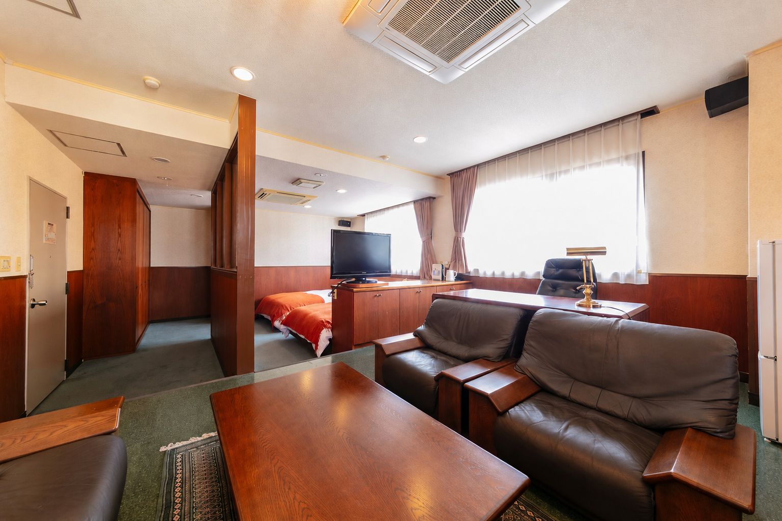 Une chambre d’hôtel avec un canapé, un bureau, une télévision et un lit.