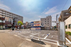 A parking lot with marked spaces and a sign indicating parking rates. - Mango Hotel Nichinan (Nichinan)