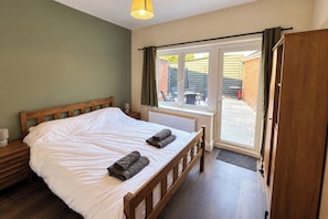 Un dormitorio con cama de madera, mesita de noche, ventana con cortinas y vistas al exterior.