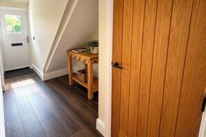 A hallway with a wooden door, a small wooden table with a basket, and a radiator.