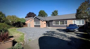 A residential property with a driveway, a car parked in the driveway, and a house with a brick facade and a garage.