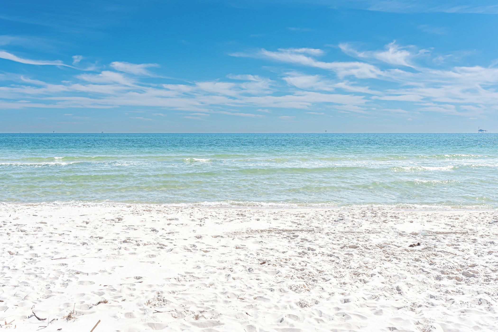 Una playa con cielos despejados y aguas tranquilas.