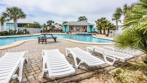 A swimming pool with lounge chairs and a picnic table, surrounded by palm trees and buildings. - 5002 Rookery 1/4 mile beach 2 pools (Gulf Shores)