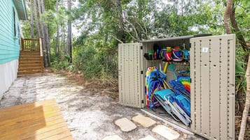 Un depósito de almacenamiento con varios objetos, incluyendo una kayak, una tabla de remo y una canoa.