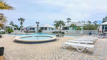 Un área de piscina con sillones reclinables y un jacuzzi.