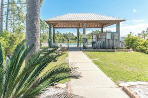 A gazebo with a roof, a pathway leading to it, and a fenced pool area with chairs. - 5003 Rookery 3 The Sea Pearl (Gulf Shores)