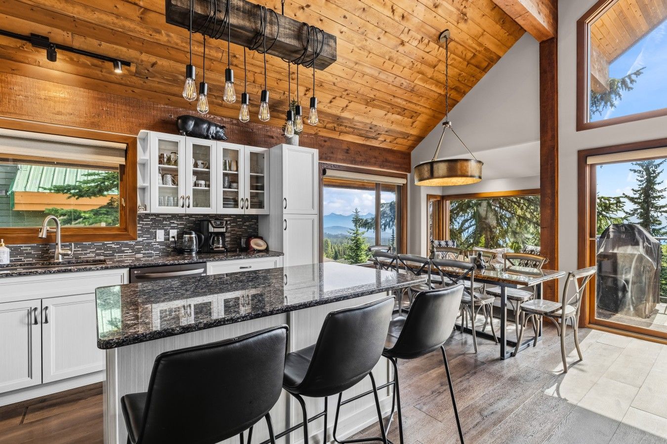 Une cuisine moderne dotée d’un grand îlot central, de tabourets de bar et offrant une vue sur l’extérieur.