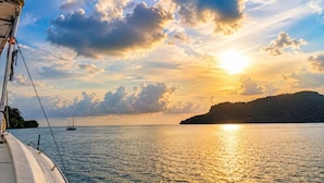 A boat on calm waters with a sunset and a distant island.