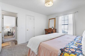 A bedroom with a bed, a dresser, a mirror, and a door leading to another room. - Furnished Executive Stay Offers 2 Living, 2 King 1 Queen Private Primary Suite (Tulsa)