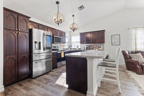Une cuisine moderne avec des meubles en bois foncé, des appareils électroménagers en acier inoxydable et un îlot central.