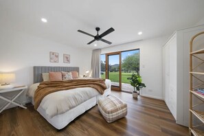 Ein Schlafzimmer mit Bett, Nachttisch und Blick ins Freie.