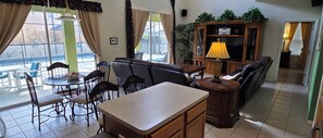 A dining area with a table and chairs, a sofa, a TV, and a lamp. - Spacious 6-bedroom house just 10 minutes from Disney property (Kissimmee)