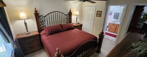 A bedroom with a bed, bedside tables, a nightstand, a ceiling fan, and a door leading to a bathroom. - Spacious 6-bedroom house just 10 minutes from Disney property (Kissimmee)