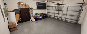 A garage with a closed garage door, a wooden cabinet, and various items including a stroller and boxes. - Spacious 6-bedroom house just 10 minutes from Disney property (Kissimmee)