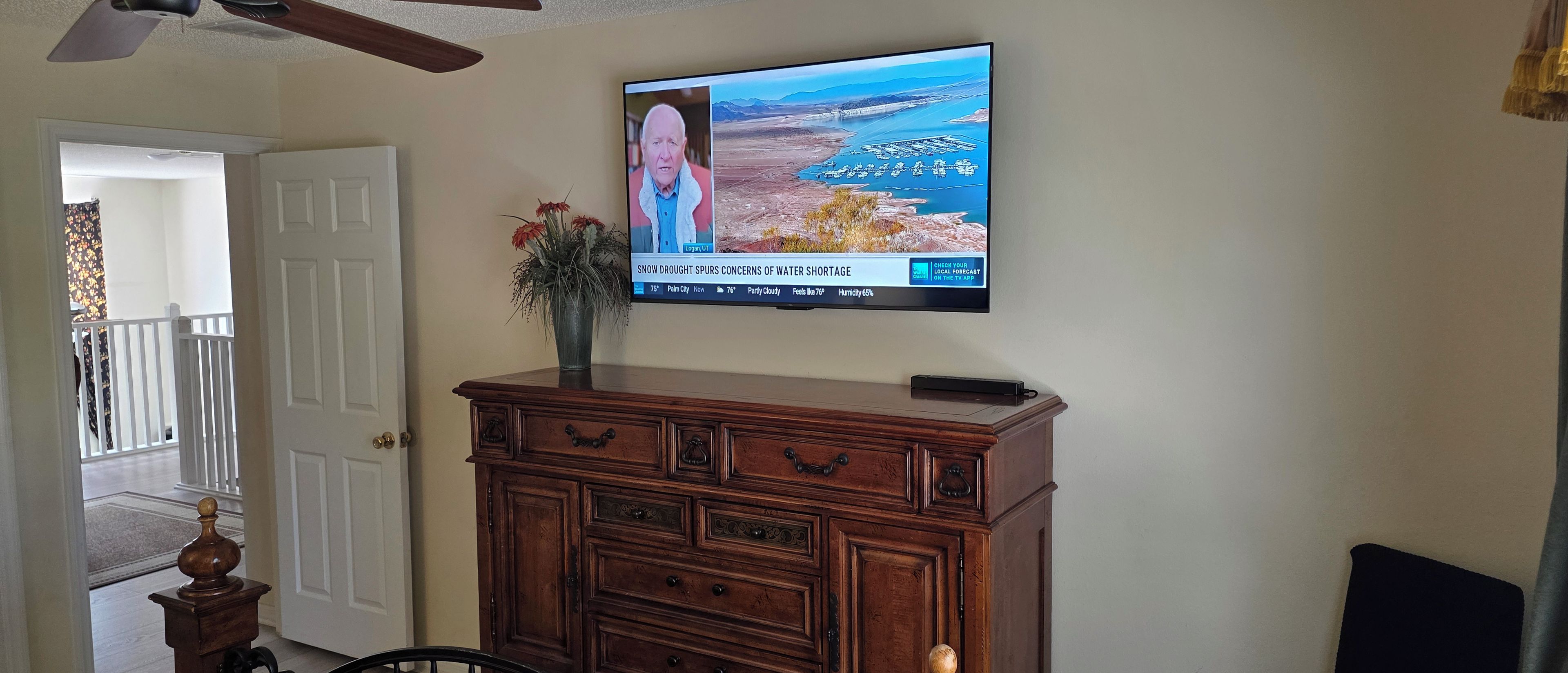 A television mounted on a wall displaying a weather forecast.