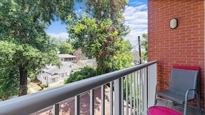 A balcony with a metal railing, a red chair, and a view of neighboring houses and trees. - Crimson Cajun | Where Southern Comfort Meets Football (Tuscaloosa)