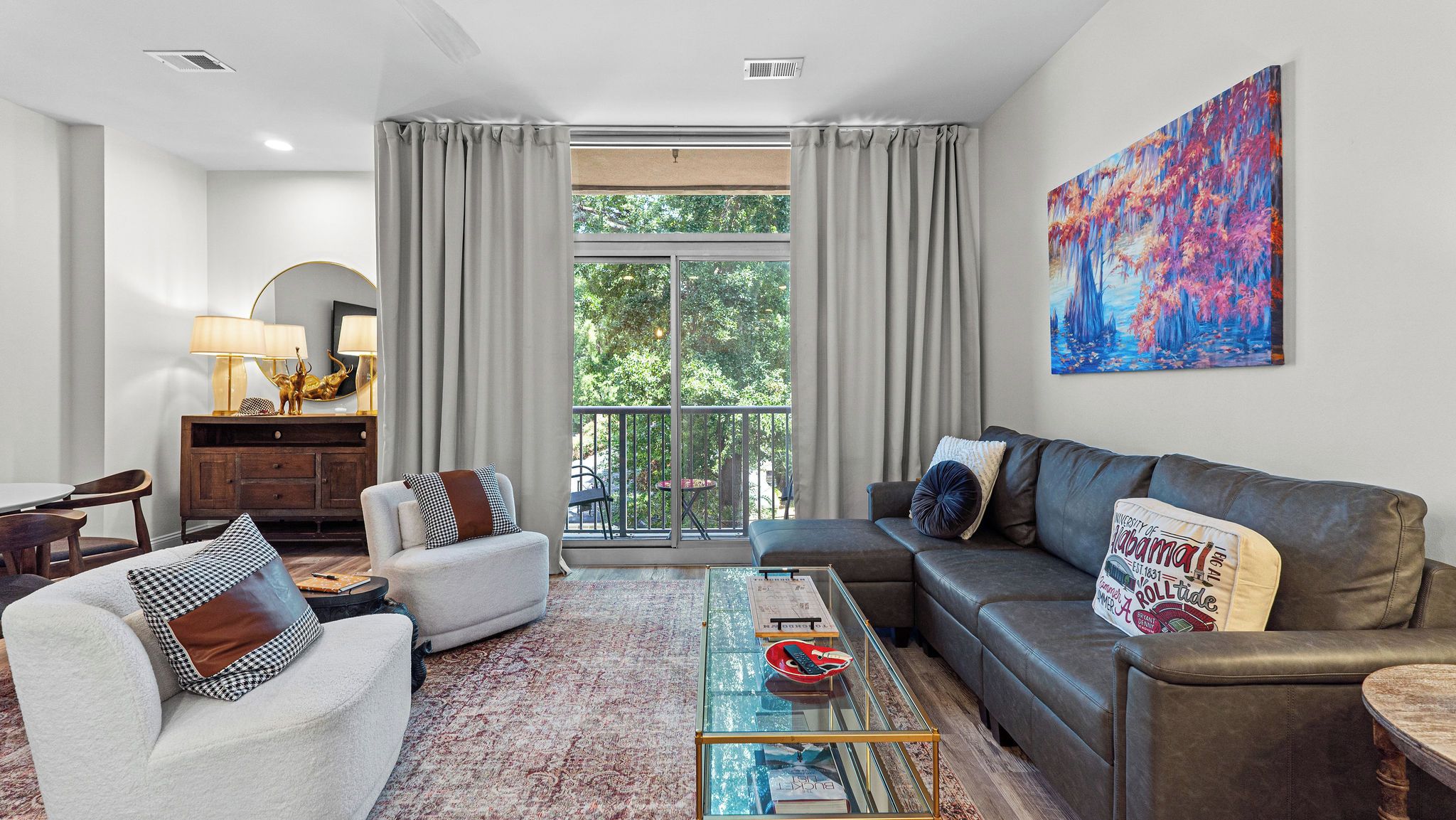 A modern living room with a sofa, armchairs, a coffee table, and a bookshelf.