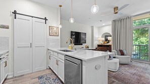 A modern kitchen with a central island, white cabinetry, and a built-in dishwasher. - Crimson Cajun | Where Southern Comfort Meets Football (Tuscaloosa)