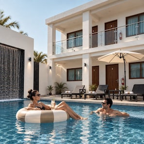 A swimming pool area with lounge chairs and a building with balconies.