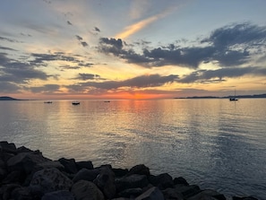 A calm body of water with boats and a rocky shoreline.