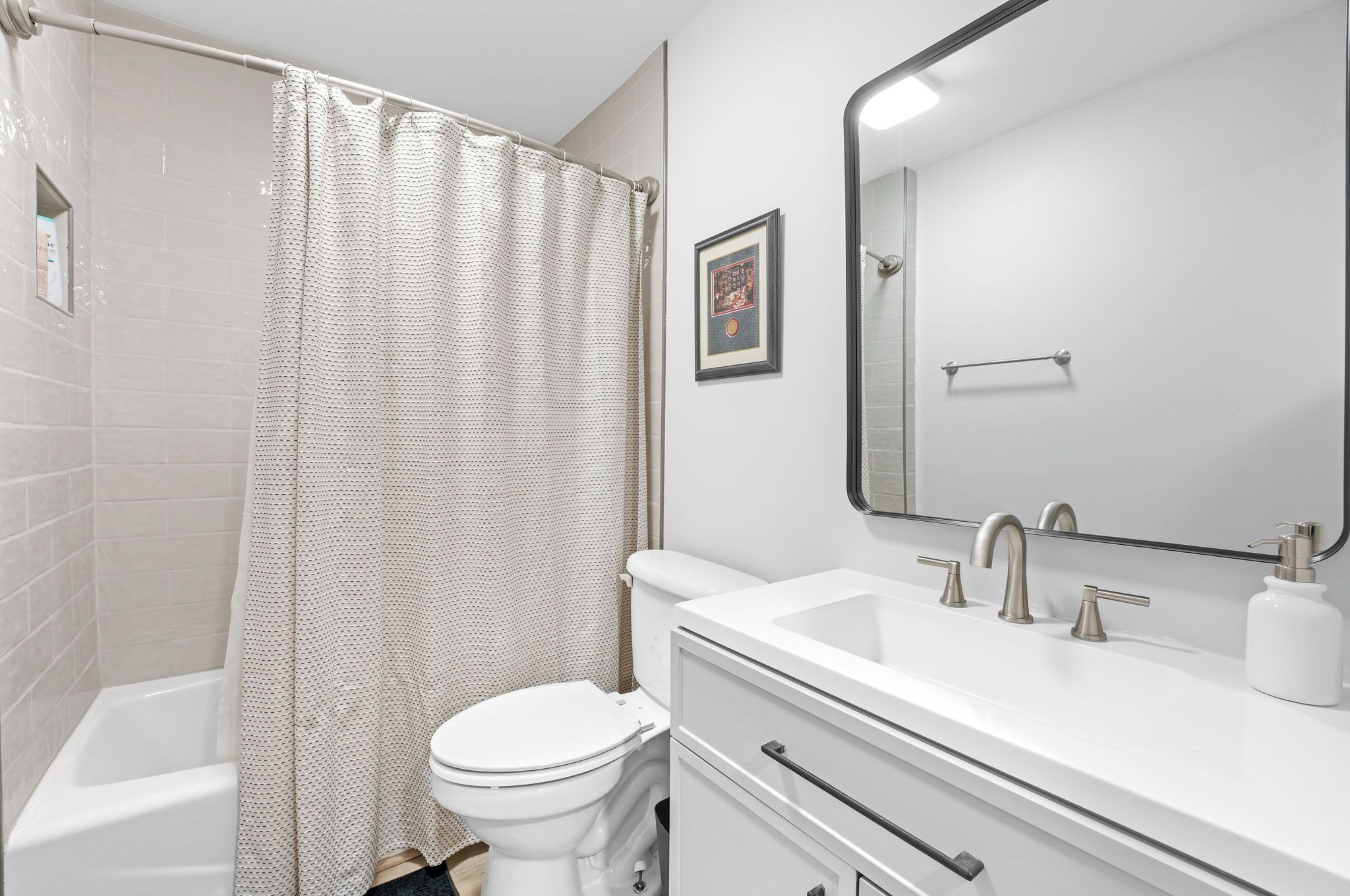 A modern bathroom with a shower, toilet, sink, and a large mirror.