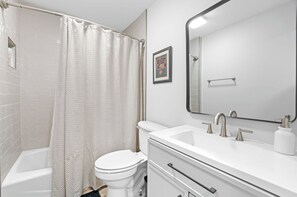 A modern bathroom with a shower, toilet, sink, and a large mirror. - Legacy Retreat | Walk to Bryant-Denny (Tuscaloosa)