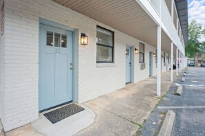A row of white brick buildings with light blue doors, numbered 32 and 33, and a covered walkway. - Legacy Retreat | Walk to Bryant-Denny (Tuscaloosa)