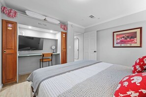 A bedroom with a bed, a desk, a chair, a mirror, and a framed picture on the wall. - Legacy Retreat | Walk to Bryant-Denny (Tuscaloosa)