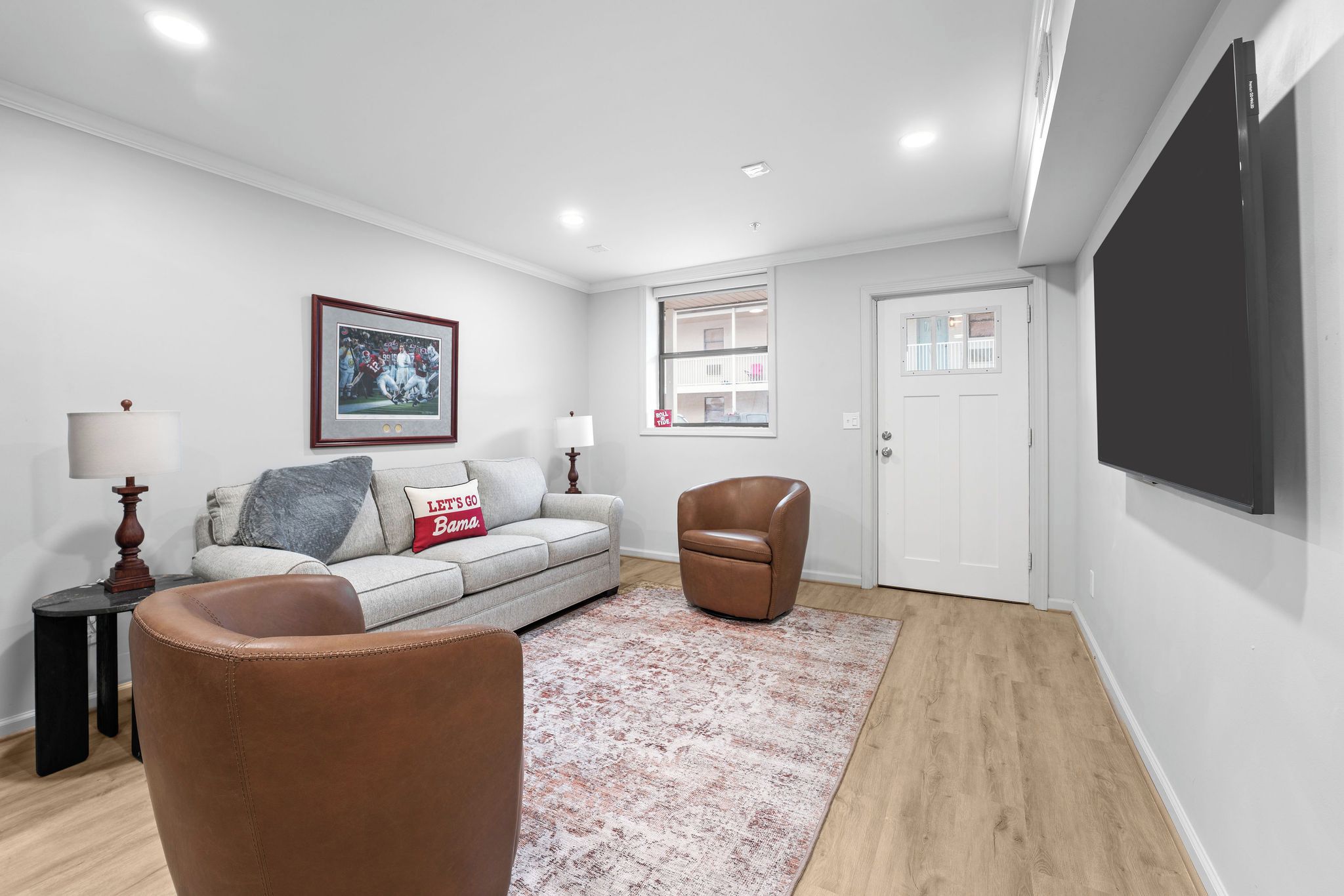 A modern living room with a sofa, armchair, and a flat-screen TV mounted on the wall.