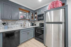 A kitchen with grey cabinets, a stainless steel refrigerator, a microwave, and a stove. - Legacy Retreat | Walk to Bryant-Denny (Tuscaloosa)